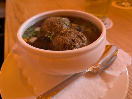 Schüssel mit Leberknödelsuppe mit frischen Kräutern.
