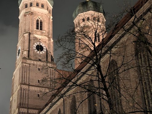 Die Frauenkirche München bei Nacht vor dunklem Himmel.