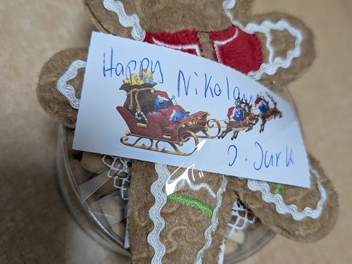 Lebkuchenmann mit handgeschriebener Nikolaus-Grußkarte auf einer Keksdose.