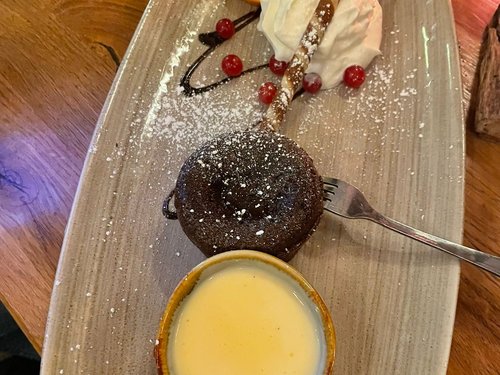 Schokoladen-Soufflé mit Puderzucker, Sahne, Orangenscheibe und Preiselbeeren, dazu eine Crème brûlée.