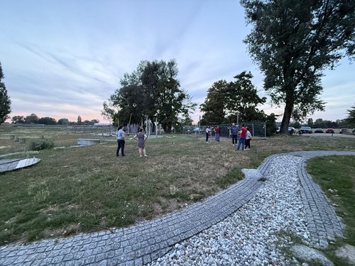 Gruppe von Kolleg:innen steht bei Sonnenuntergang auf einer Wiese am Rhein beim Hofgut Maxau.