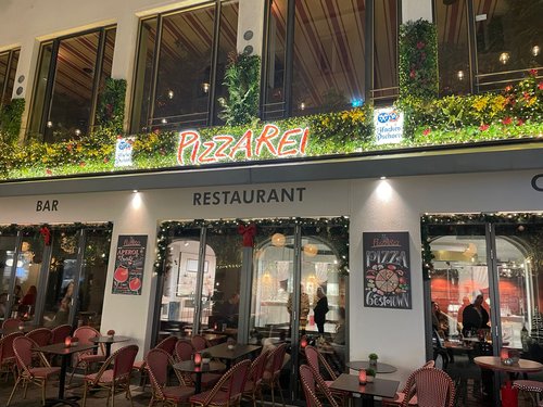 Restaurantfassade der Pizzarei bei Nacht, weihnachtlich dekoriert.
