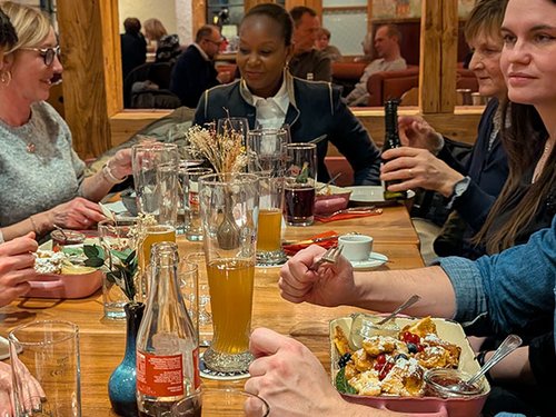 Gruppe sitzt an einer langen Tafel im Restaurant beim Essen und Trinken.