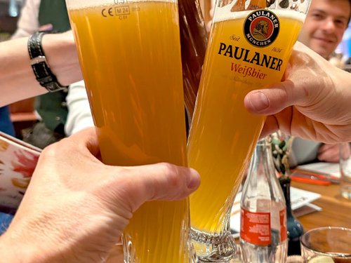 Zwei Personen stoßen mit Weißbiergläsern an.