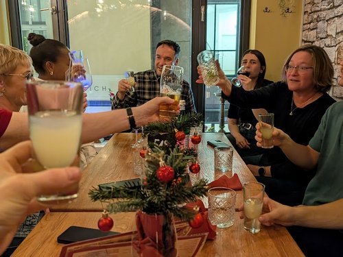 Team stößt gemeinsam mit verschiedenen Getränken an einem festlich dekorierten Tisch an.