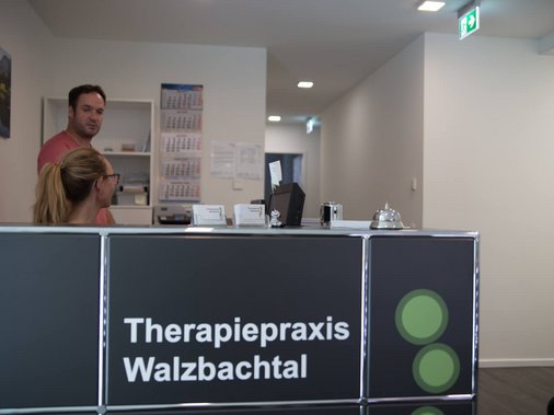 Eingangsbereich mit Glastür, Beschriftung und Blick auf einen Lieferwagen draußen.