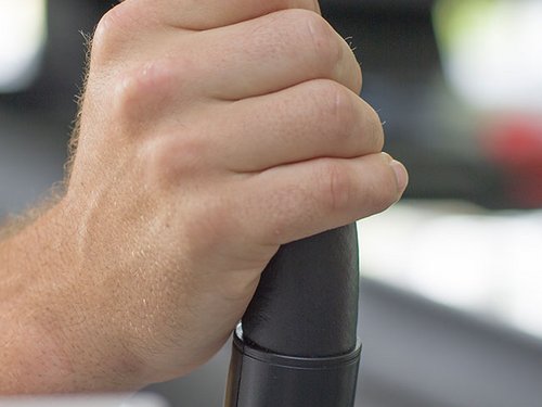 Nahaufnahme einer Hand am Haltegriff eines Laufbands.