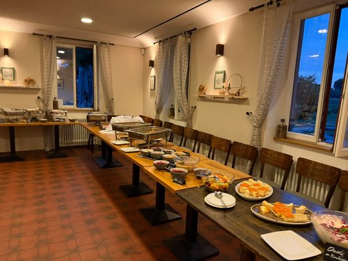 Langer festlich gedeckter Buffettisch mit Chafing Dishes in einem Innenraum des Hofguts, Blick durchs Fenster in den Abendhimmel.