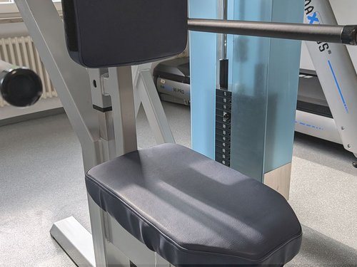 Nahaufnahme des Gewichtsgestells eines Trainingsgeräts, im Hintergrund ein Laufband.