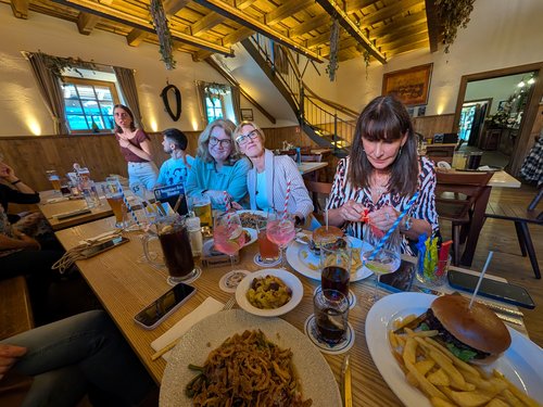 Team sitzt gemeinsam an einem langen Tisch mit Getränken, Pommes und Burger.