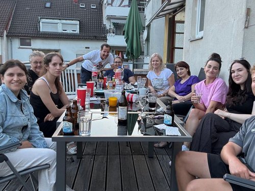Team der Physiotherapie Kretzschmar sitzt lachend zusammen auf der Dachterrasse beim Sommerfest.