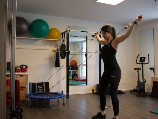 Frau trainiert am Kabelzug-Gerät im Trainingsraum.